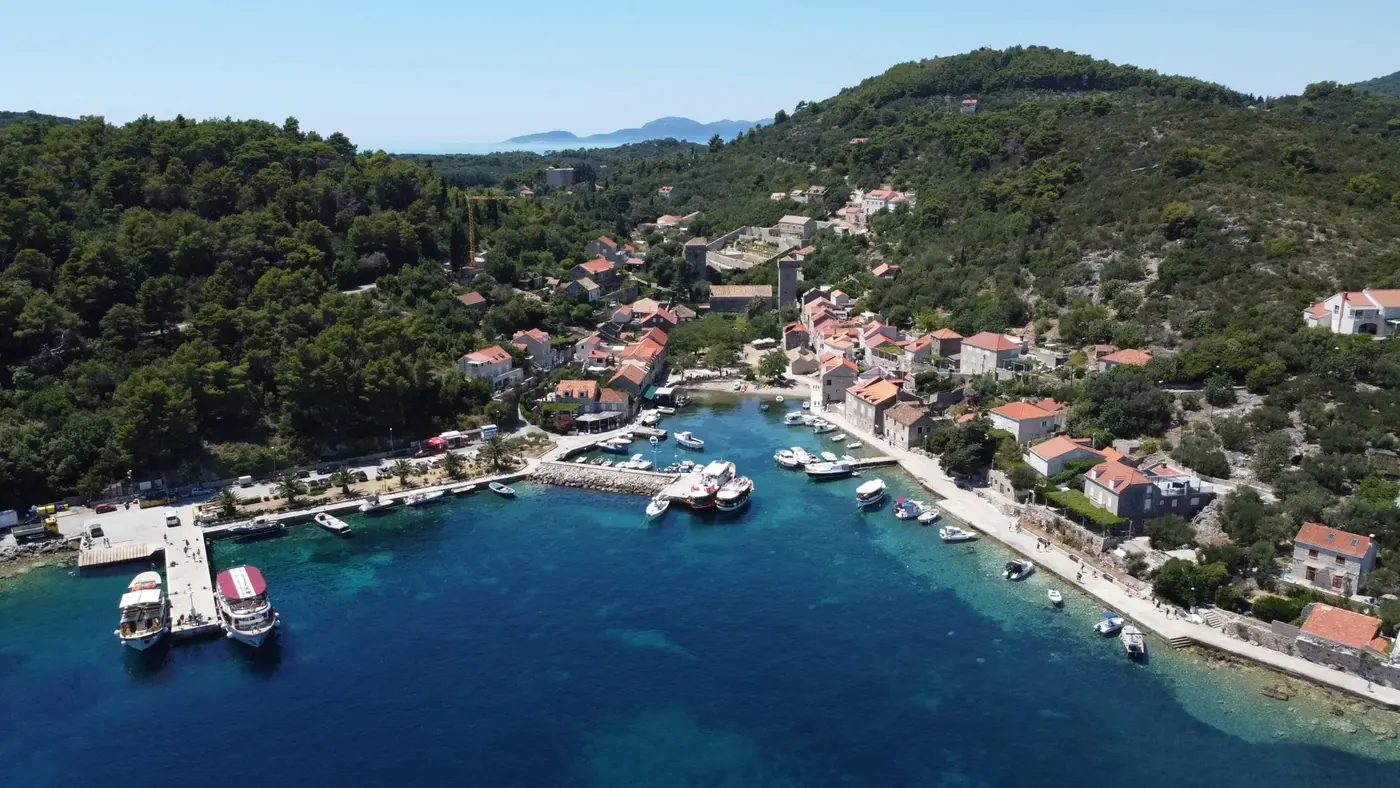 Aerial view of a village harbour on Šipan with stone houses and moored boats