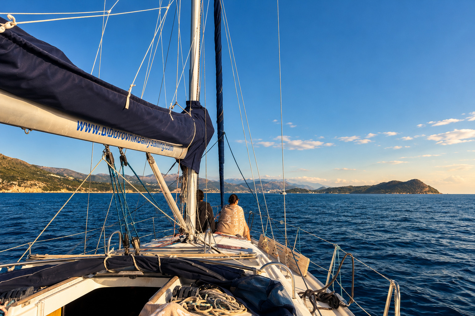 Guests on the foredeck of our sailing yacht sailing back toward Dubrovnik in late-afternoon light