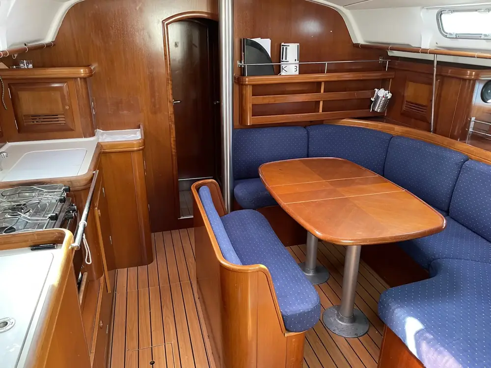Saloon of the sailing yacht with wooden table, blue seating and galley