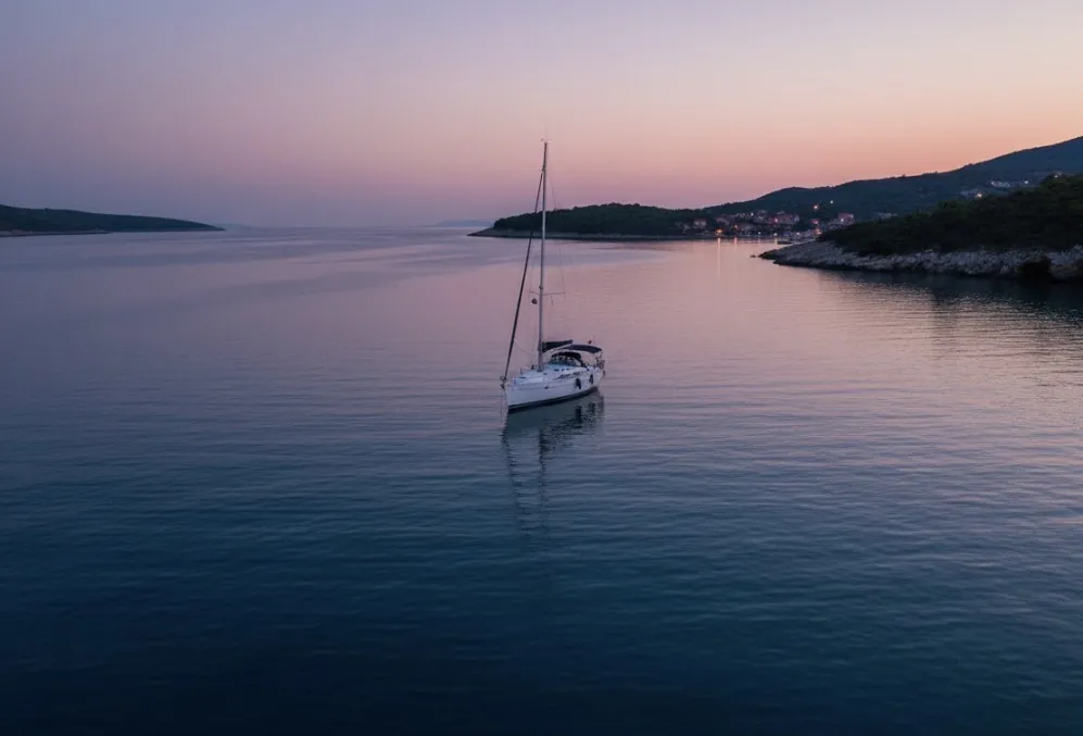 Sailing yacht at anchor in a quiet bay at sunset